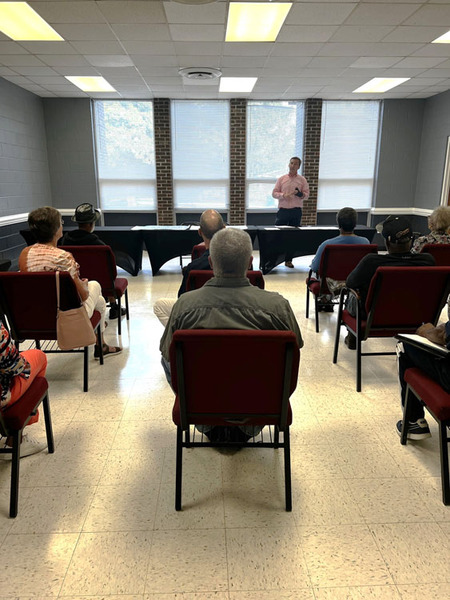 A view from the back of a meeting room with a speaker at the front.