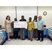 A group of individuals gather around a large oversized check.