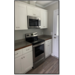 Kitchen view of counter, stove, microwave and cabinets.