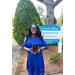 A woman stands outside holding a plaque.