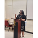 A woman at a podium speaking to an audience. A 2024 graduation decoration is on the front. 