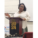 A woman is standing and speaking behind a podium with a 2024 graduation sign mounted on it. 