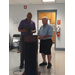 A man holding a box speaking to Mr. Davis behind a podium.