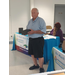 Mr. Davis standing in front of two tables holding his award with a woman in the background.