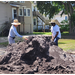 People getting dirt from a big pile.