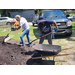 Two people with shovels filling a wheelbarrow.