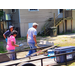 Two ladies watching a man with a wheel barrow move concrete blocks.