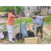 Two people filling a wooden frame to make a garden bed.