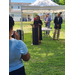 A woman at a podium speaking while people look on.