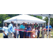 A group of people standing around a tent for a ribbon cutting. 