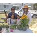 Group of people smiling  around plants. They are holding garden tools. 