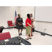 Three woman standing around a podium while one  becomes an FSS Graduate.