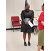 Woman standing  holding an envelope and a plaque.