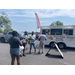 People standing outside of a food truck in the parking lot. 