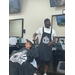 A young man getting his hair cut by a barber in an apron. 