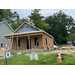 Construction on a new home with ladders, for sale sign and a traffic cone out front. 