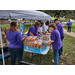 Hot dogs, bags of chips, and brown bags being put together by assorted people.