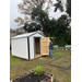 A man standing next to the open door of the new starage shed.