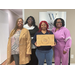 A woman standing with others holding a cutting board that reads Home Sweet Home.