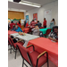 A group sitting at a table with a group standing in line for food.