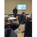 Multiple tables of staff during the presentation in the conference room.